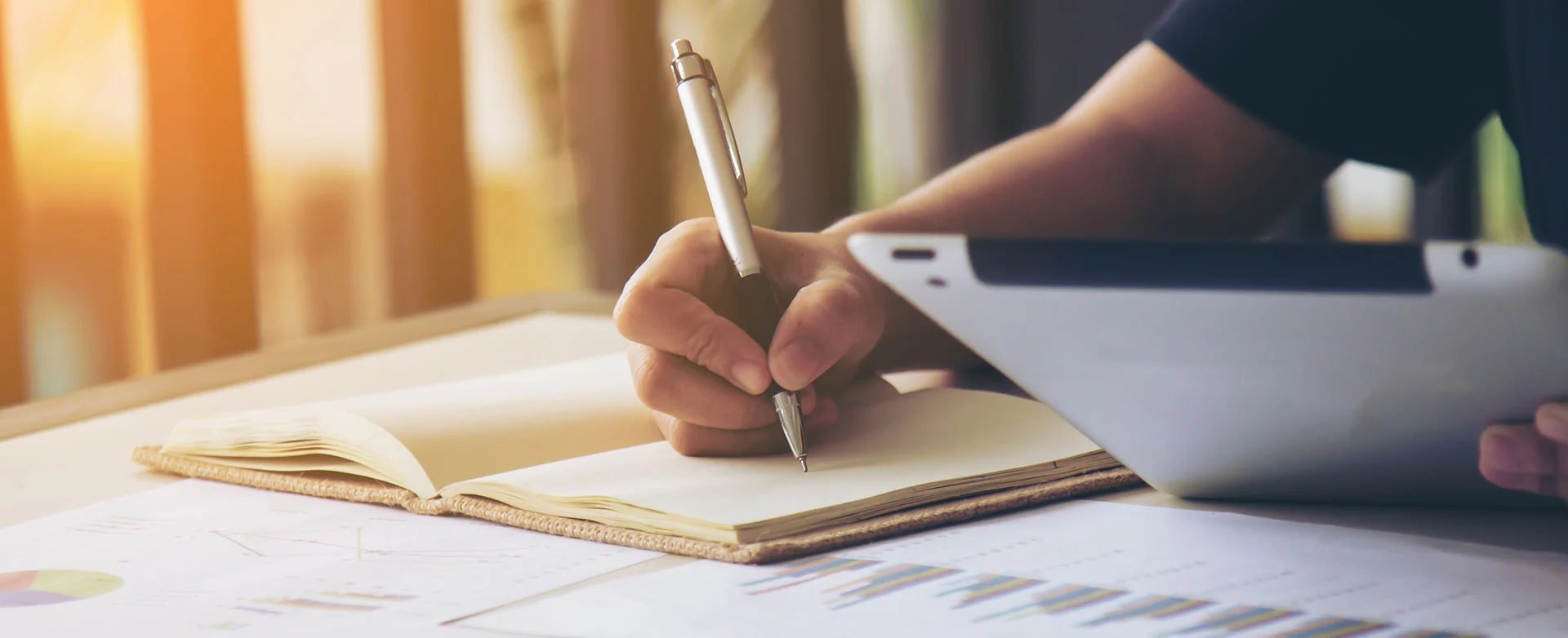 Professional reviewing documents beside a tablet